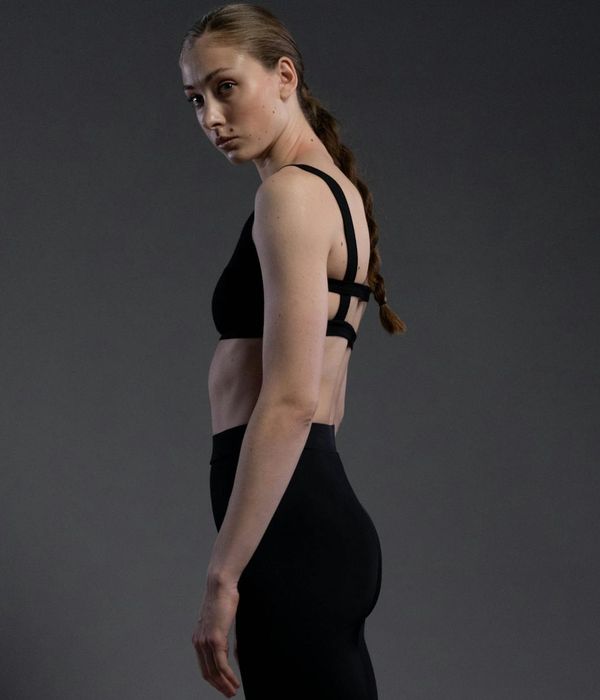 Woman in a calm yoga pose against a dark, minimalist background.